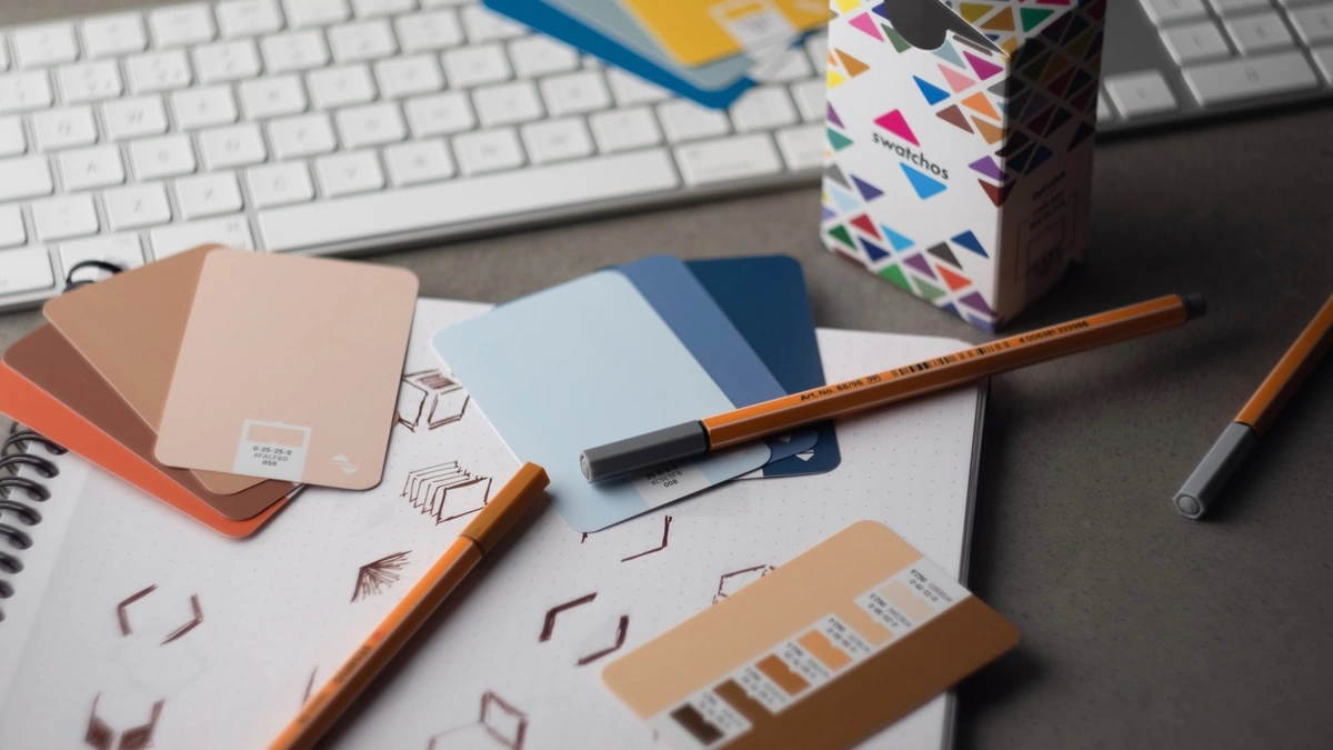 Designer workspace with color swatches, pencils, and sketch notebook