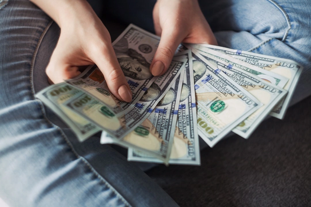 Hands holding many 100 dollar bills
